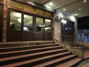 A building entrance with wooden steps and a sign above the door.