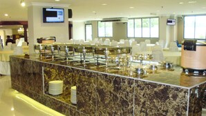 A buffet area with a marble counter, multiple serving stations, and a television screen mounted on the wall. - Eagle Bay Hotel (Langkawi)