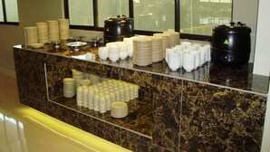 A buffet counter with stacks of plates, bowls, and cups. - Eagle Bay Hotel (Langkawi)