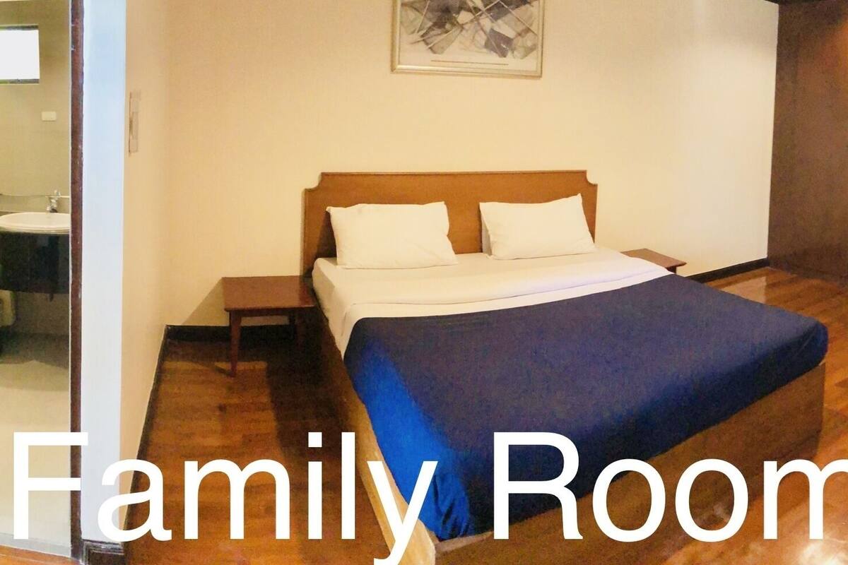 Ein Familienzimmer mit Bett, Sessel, kleinem Tisch und Spiegel.