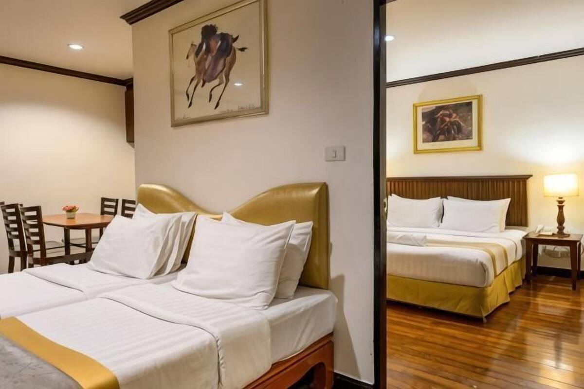 Ein Hotelzimmer mit zwei Betten, einem Esstisch, Stühlen und Kunstwerken an den Wänden.