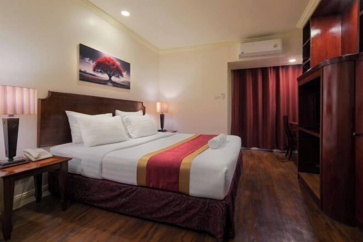 Ein Hotelzimmer mit Bett, Nachttischlampen, Telefon, einem Gemälde an der Wand und einem Kleiderschrank.