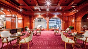 A hotel lobby with a red carpet, wooden furniture, and arched windows. - The Victory Executive Residences (Bangkok)
