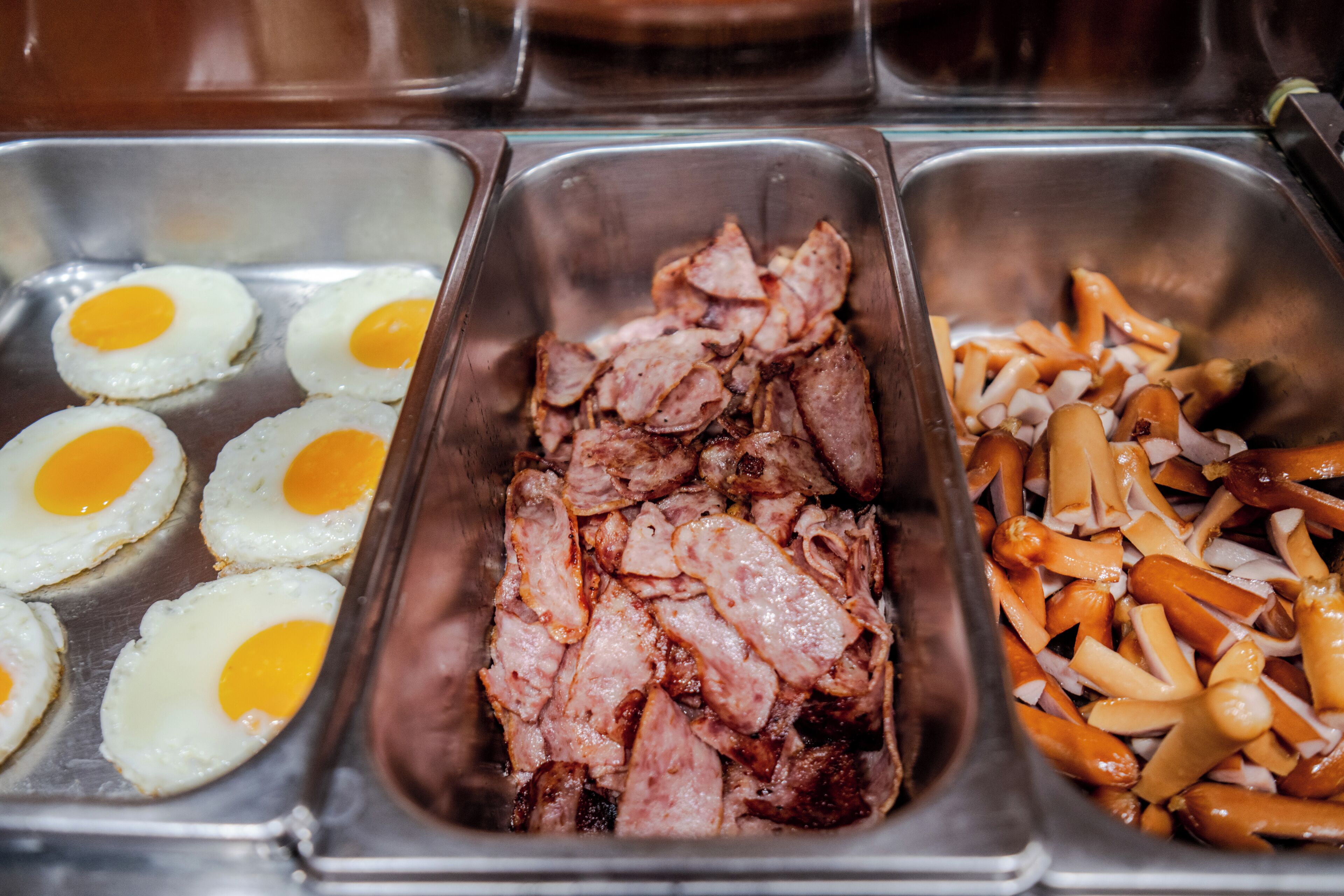 A buffet with cooked eggs, sliced meat, and sliced carrots.
