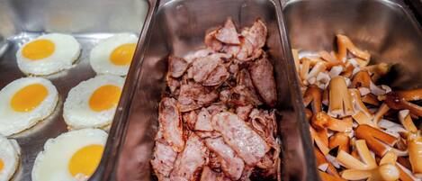 A buffet with cooked eggs, sliced meat, and sliced carrots.