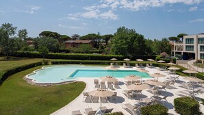 A swimming pool with lounge chairs and umbrellas, surrounded by greenery and buildings. - Smy Pisa Plaza (Pisa)