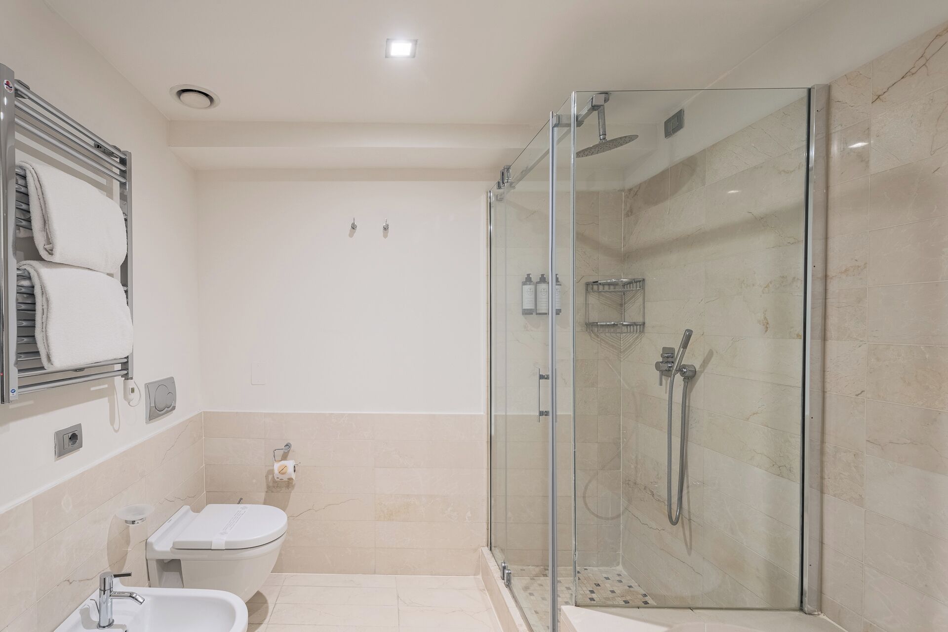 A modern bathroom with a glass-enclosed shower, a toilet, and a sink.