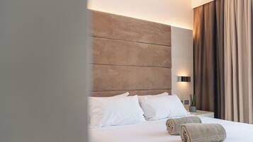 A hotel room with a large bed, white bedding, a headboard, and a nightstand with a lamp.