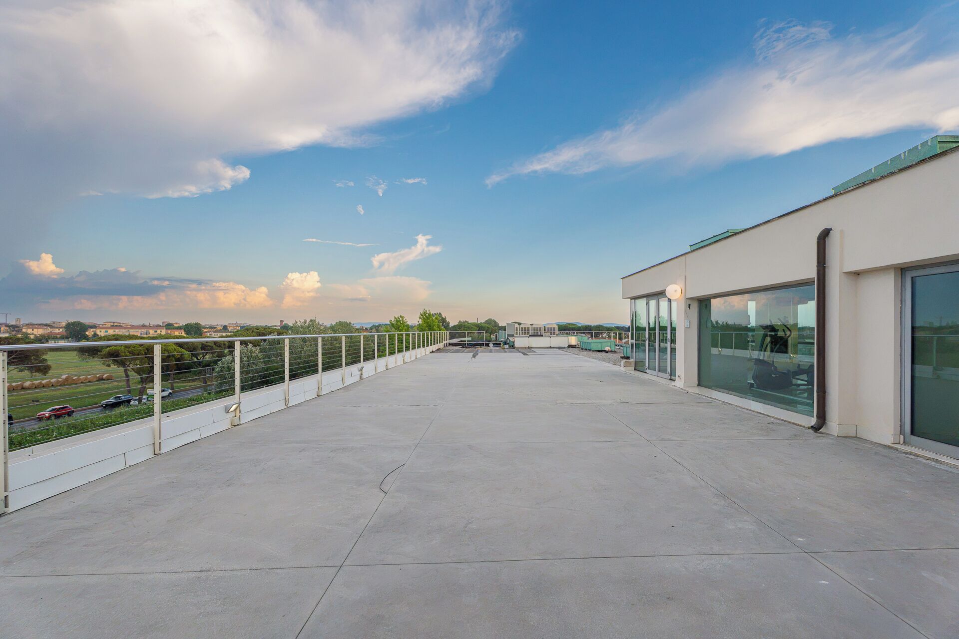 Una terrazza sul tetto con vista panoramica sulla città, un edificio in vetro e una ringhiera in metallo.