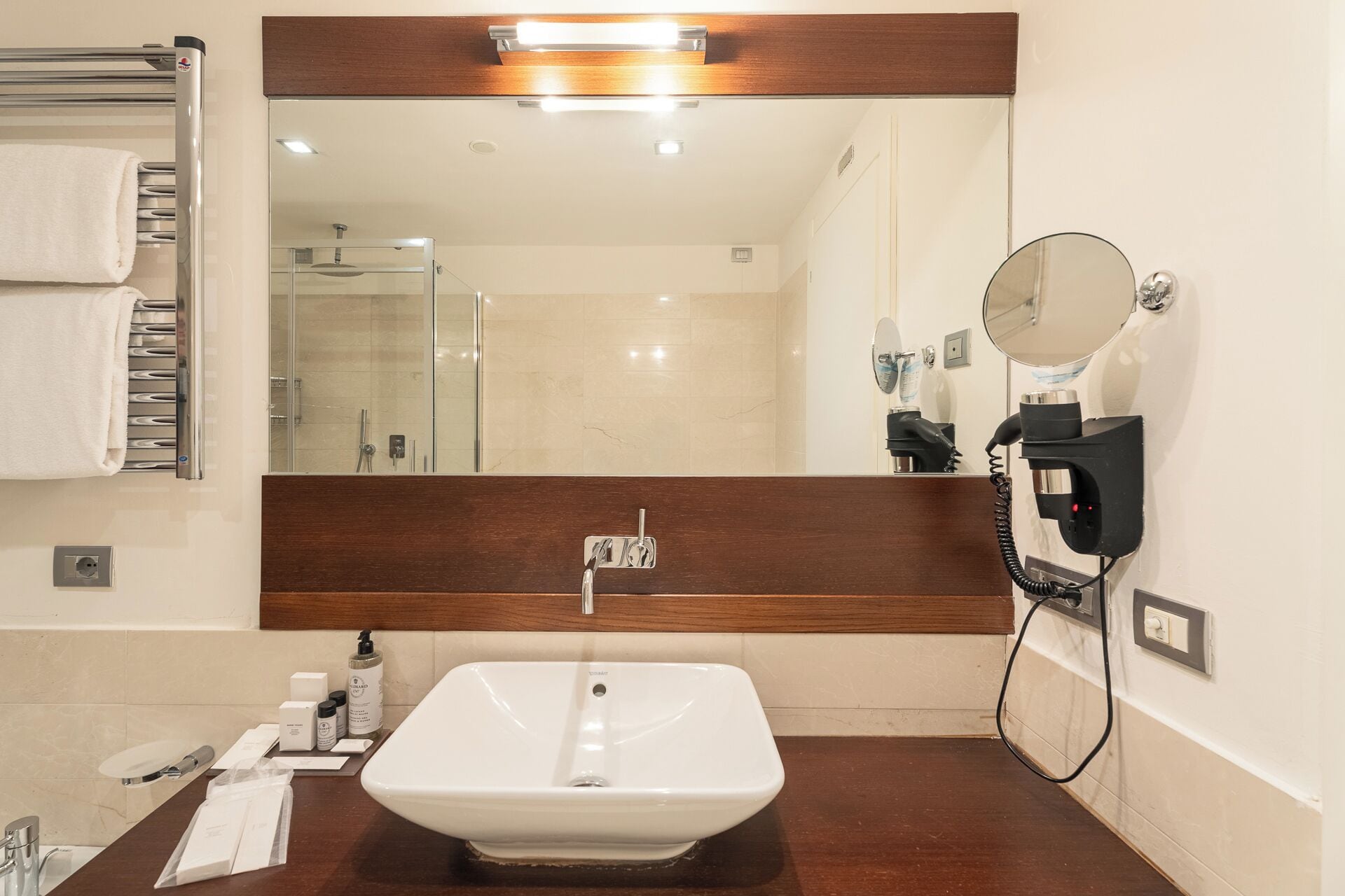 Une salle de bain avec un lavabo blanc, un porte-serviettes, un miroir et un sèche-cheveux fixé au mur.