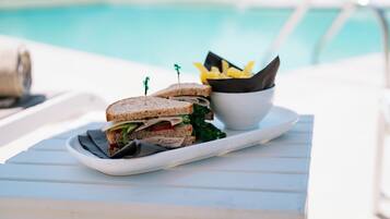 Un panino su un vassoio bianco, con una piscina sullo sfondo.