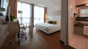 Een hotelkamer met een bed, bureau, stoel, raam met uitzicht en een badkamer.