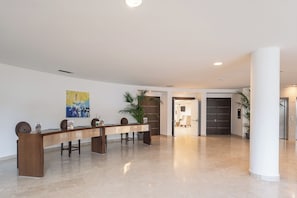Un hall d’entrée spacieux, doté d’un long comptoir de réception, d’un grand tableau abstrait et d’une porte moderne.