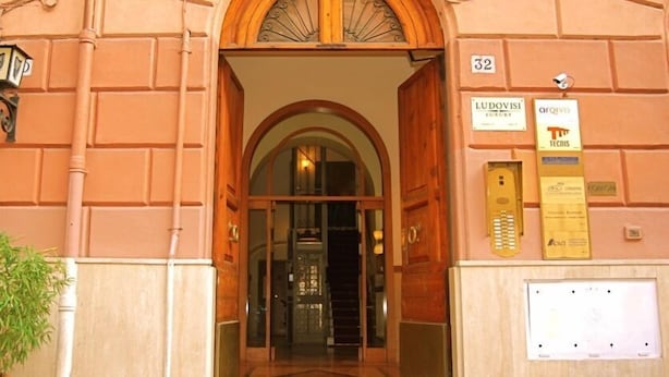 Una entrada con un arco de madera, un puerta de cristal y un cartel que indica la habitación número 32.
