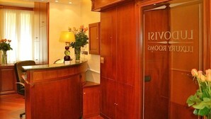 Un hall de hotel con mostrador de recepción, un armario de madera y una señal en la pared.