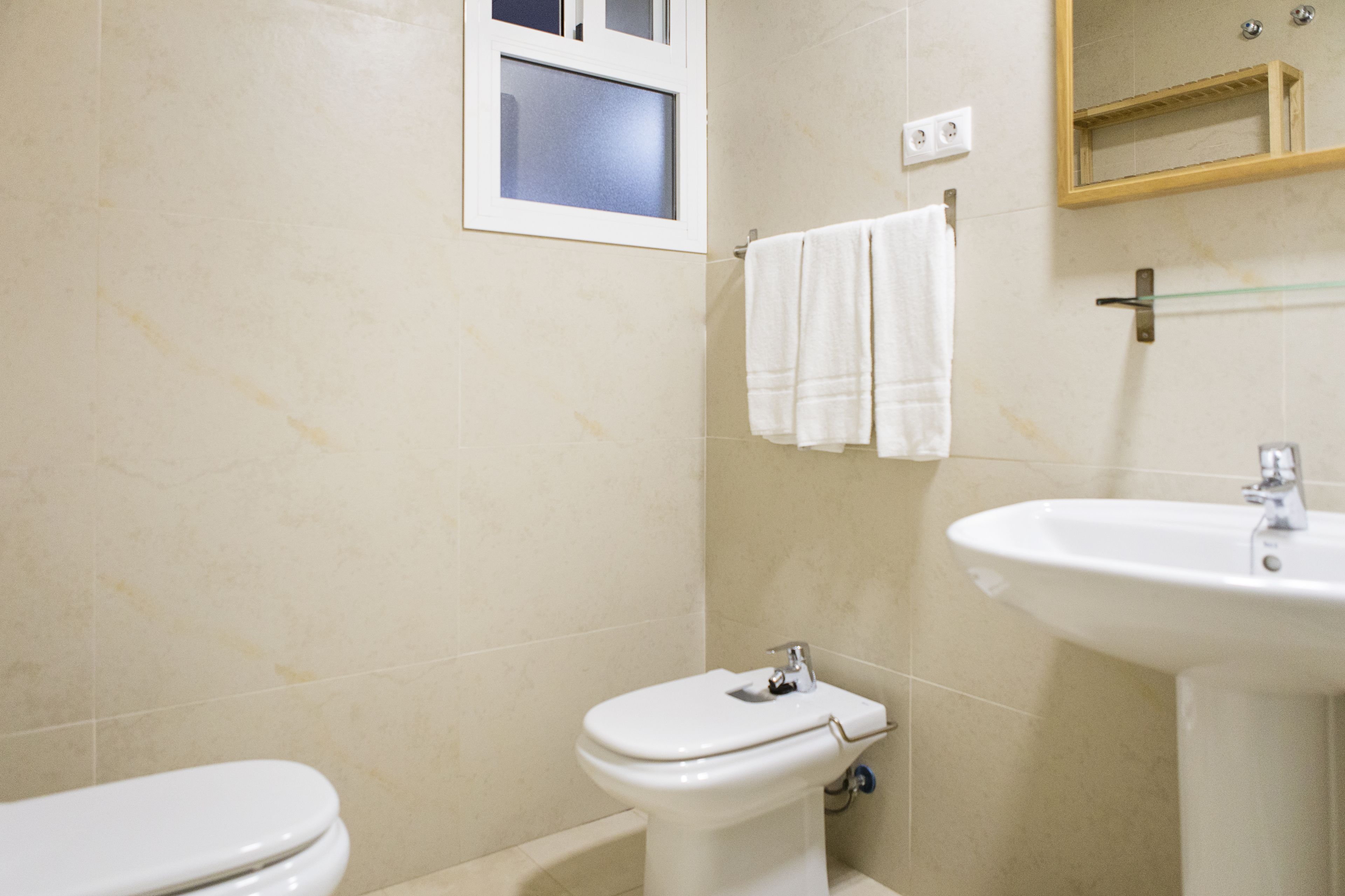 Un baño con inodoro, lavabo y ventana.