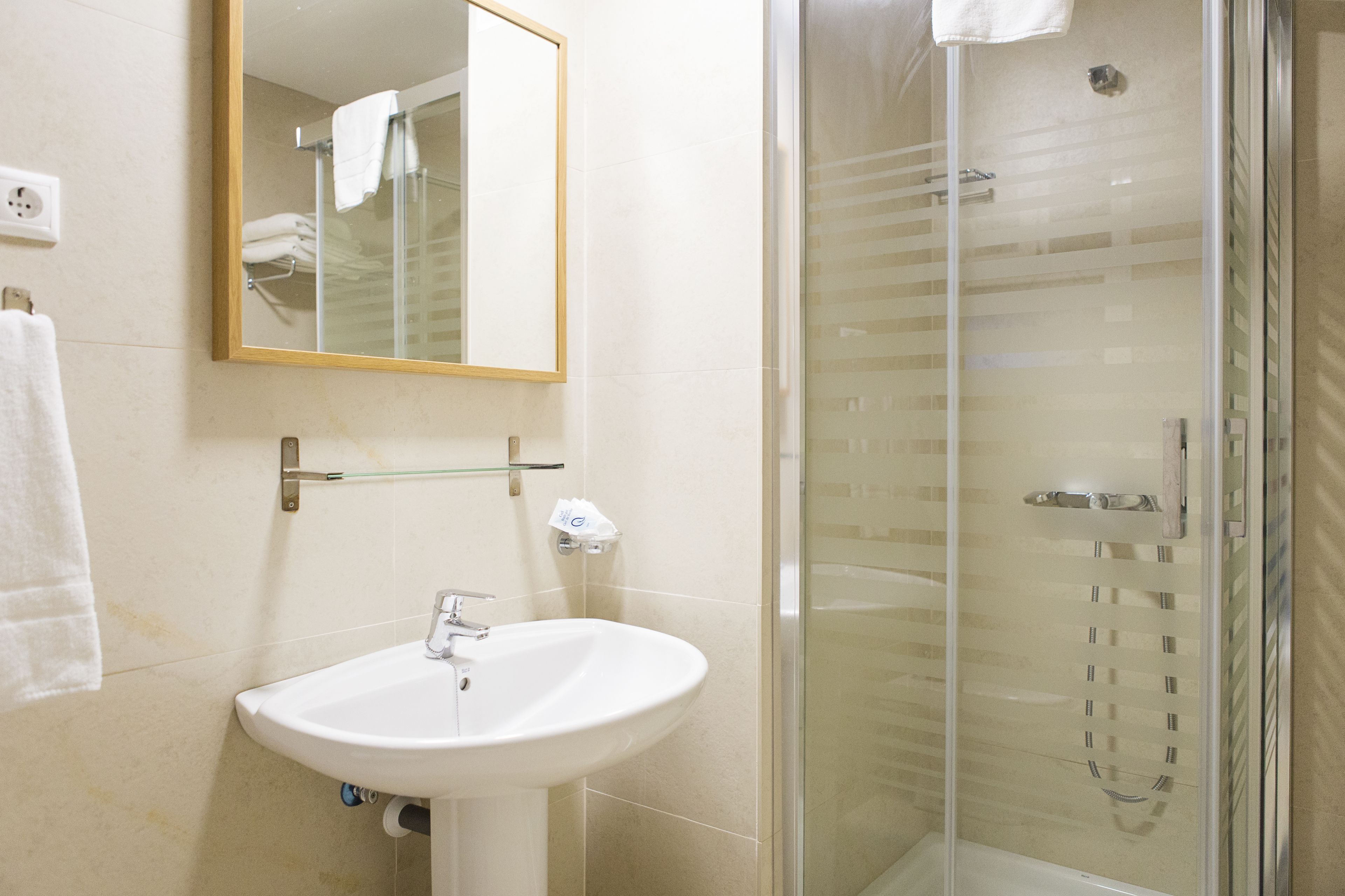 A bathroom with a sink, mirror, and glass shower enclosure.