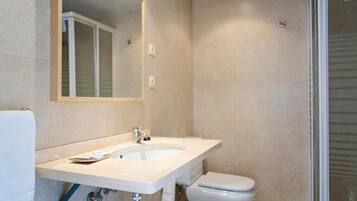 Un baño con lavamanos, espejo y retrete blanco.