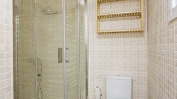 Un baño con ducha de vidrio, inodoro y perchero para toallas.