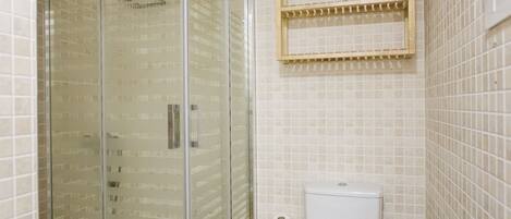 Une salle de bain avec une douche à parois de verre, des toilettes et un porte-serviettes.