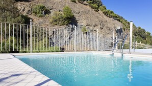Una piscina con un borde de baldosas blancas y una valla metálica.