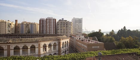 Un paysage urbain mêlant bâtiments modernes et traditionnels, dont un immeuble remarquable avec des fenêtres en arc de cercle et un toit recouvert de tuiles.