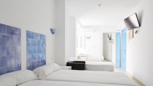 Habitación de hotel con dos camas, un televisor montado en la pared y un baño visible a través de una puerta abierta.