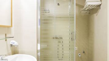 Ein Badezimmer mit Duschkabine, Waschbecken und Handtuchhalter.