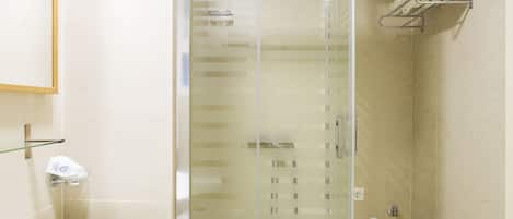 Un baño con ducha de vidrio, lavamanos y perchero para toallas.