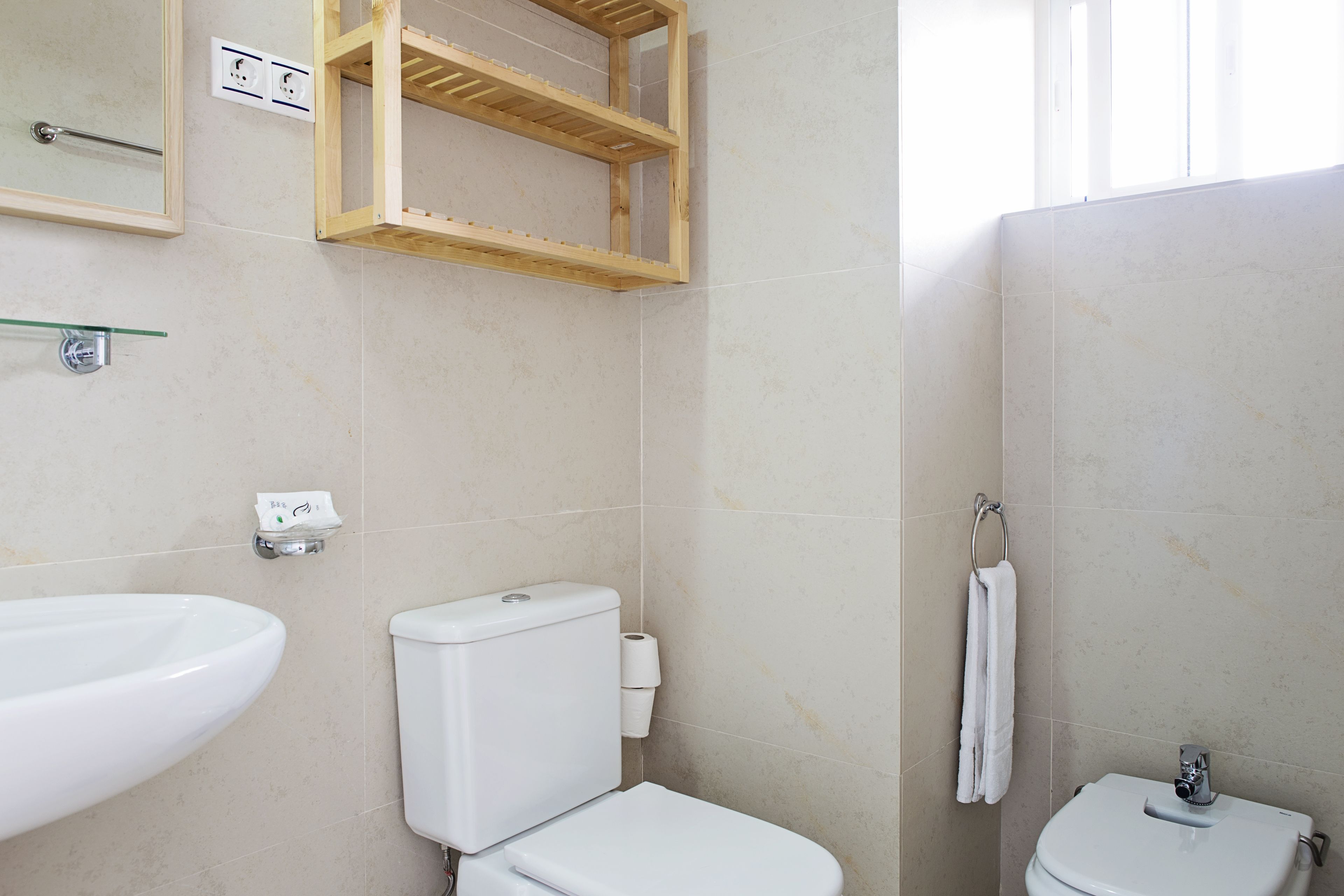 A bathroom with a sink, toilet, and a wooden shelf unit.