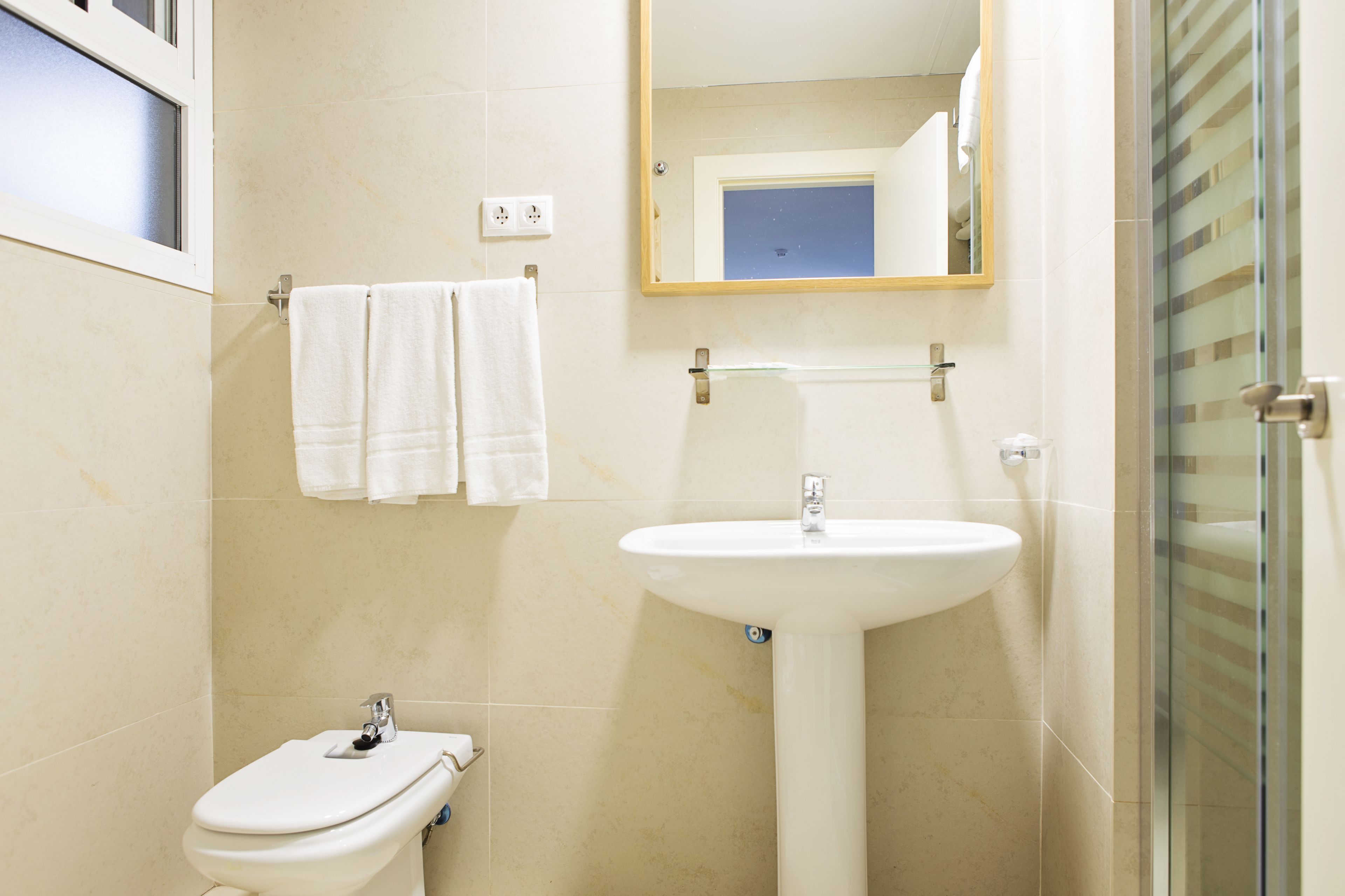 A bathroom with a toilet, sink, and a glass shower enclosure.