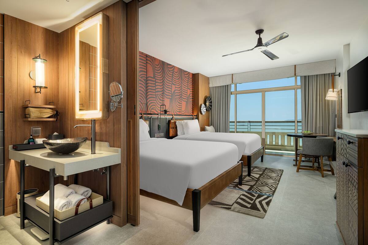Habitación de hotel con una cama grande, una tocador con espejo, un ventilador de techo y vistas al exterior.