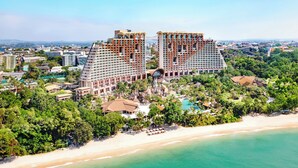 Un hotel moderno de altura con varios balcones, una playa y una zona de piscina.