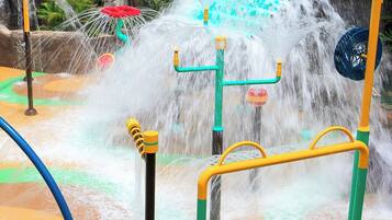 A water play area with multiple water jets and a green slide.
