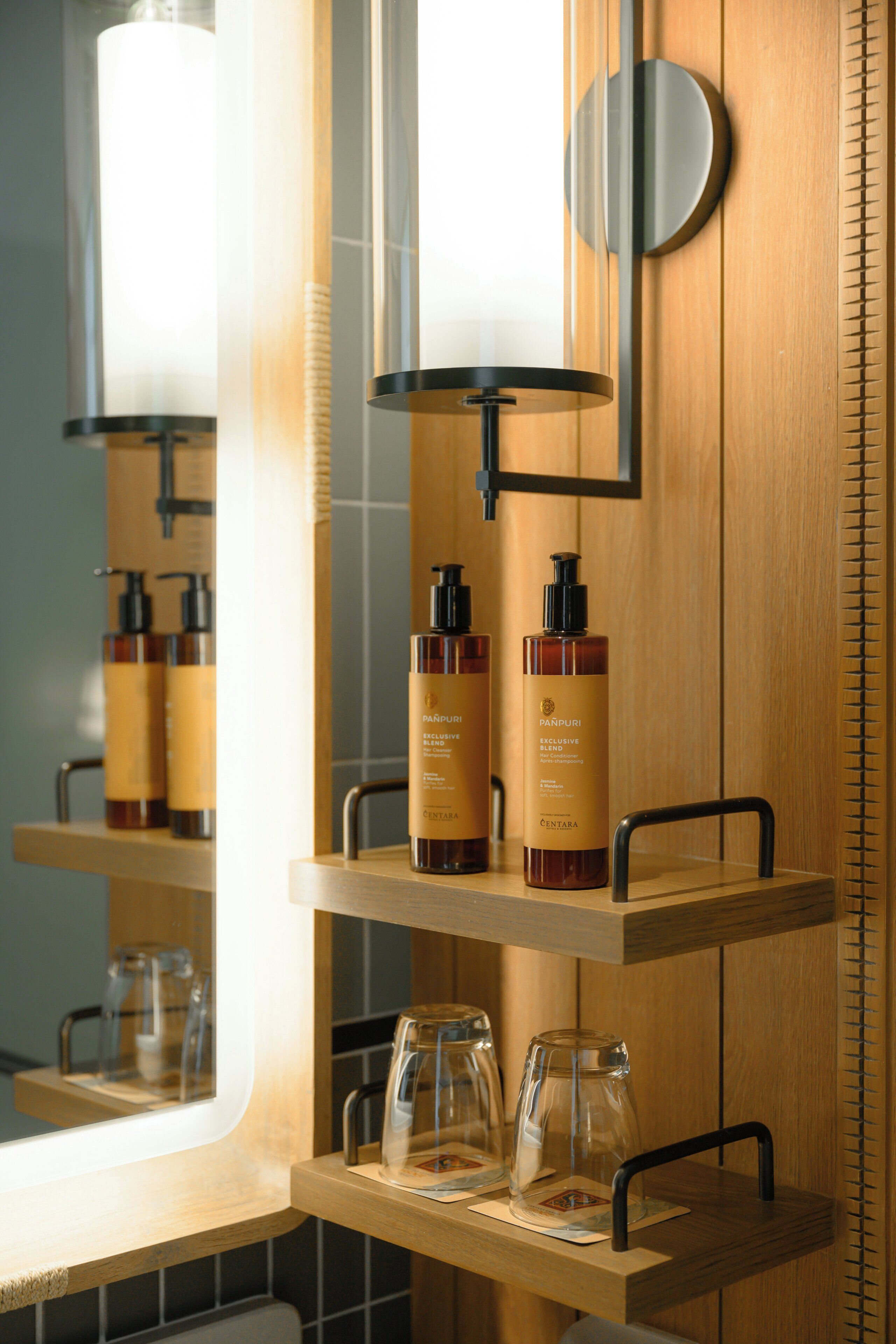 Un baño con estantes de madera que sostienen artículos de aseo personal y recipientes de vidrio.