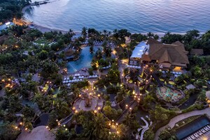 Vista aérea de un complejo turístico con una piscina grande, varias zonas de restauración y una playa.