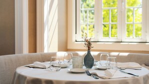 A dining table set with plates, glasses, and cutlery, a vase with dried flowers, and a textured candle holder. - Monte Real Hotel, Termas & Spa (Leiria)