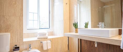 A modern bathroom with a toilet, bidet, sink, and mirror.