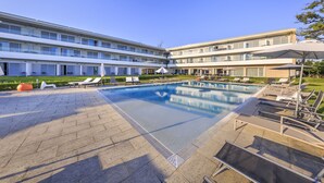 A modern hotel with a central swimming pool, multiple lounge areas, and a well-maintained garden. - Monte Real Hotel, Termas & Spa (Leiria)