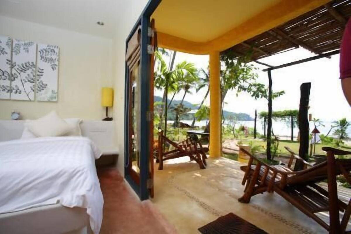 Une chambre avec un lit, un bureau et une vue sur la plage.
