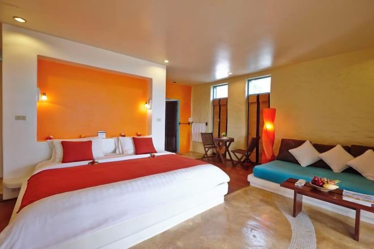 Una habitación de hotel con una cama grande, un sofá, una mesita y una silla.