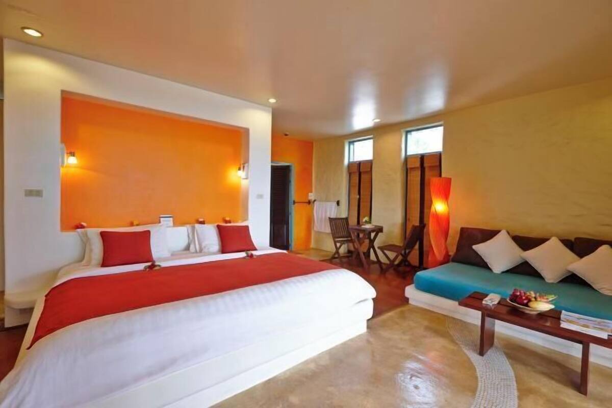 Une chambre d’hôtel avec un grand lit, un canapé, une petite table et une chaise.