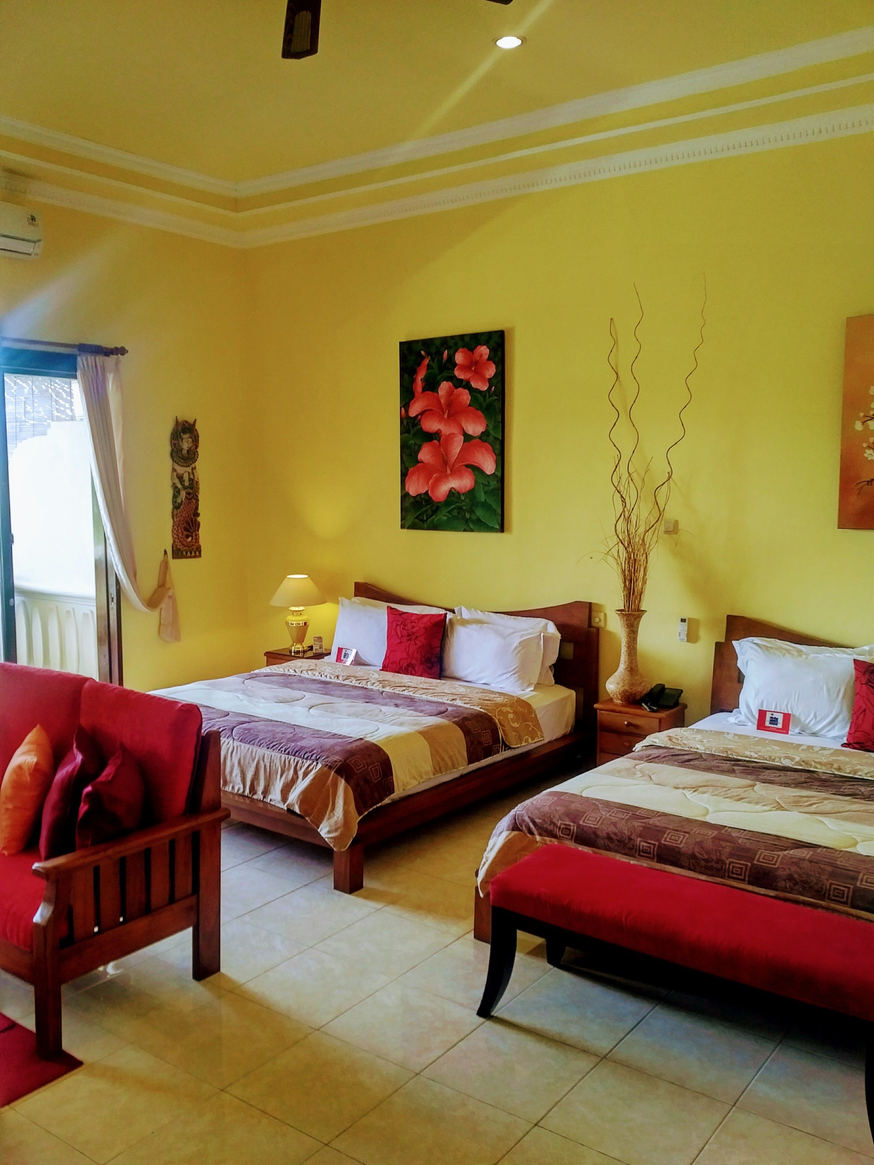 A hotel room with two beds, a wooden chair, a nightstand, and a window with curtains.