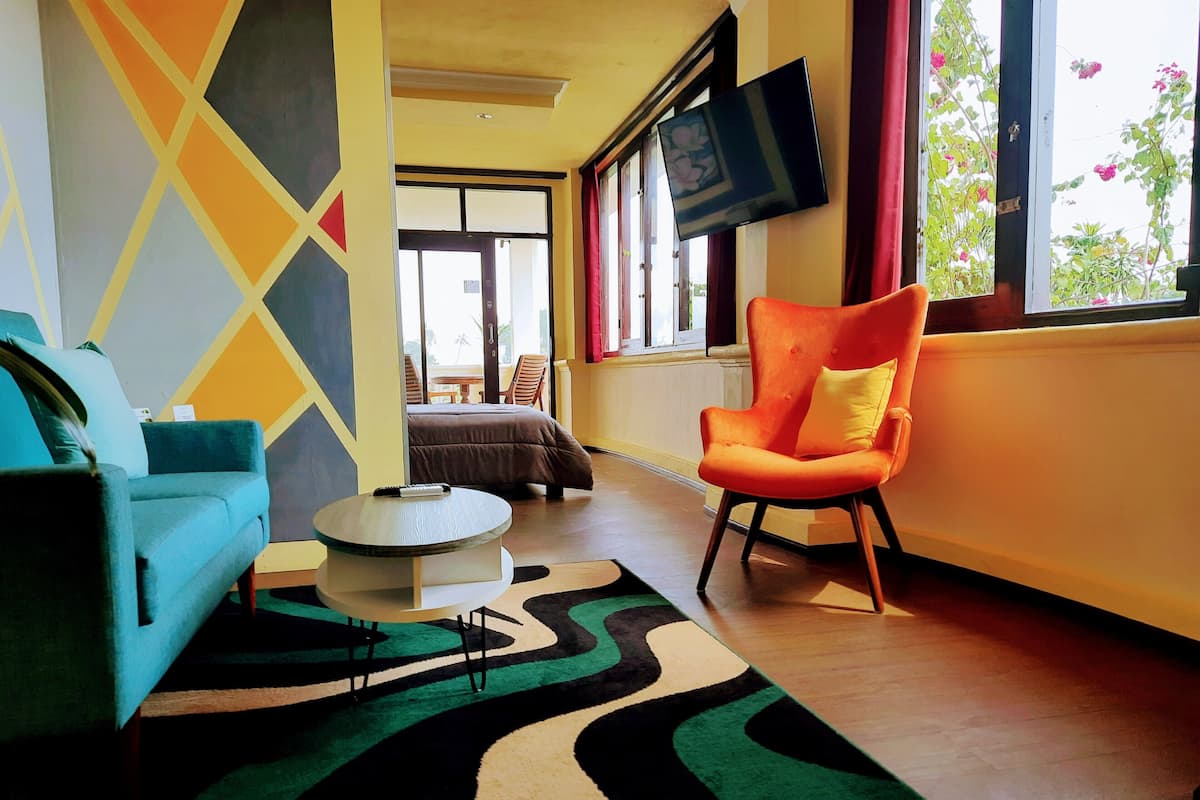 Un salon moderne comprenant un canapé, un fauteuil, une table basse et un téléviseur fixé au mur.