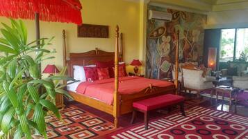 A spacious bedroom with a four-poster bed, a large red umbrella, and a vibrant floral mural.