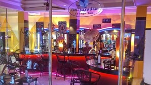 Een loungebar met modern design, met een bar, zithoek en decoratieve planten.