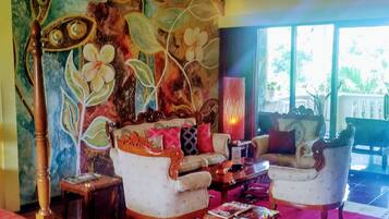 A spacious living area with a large floral mural, two armchairs, a coffee table, and a floor lamp.