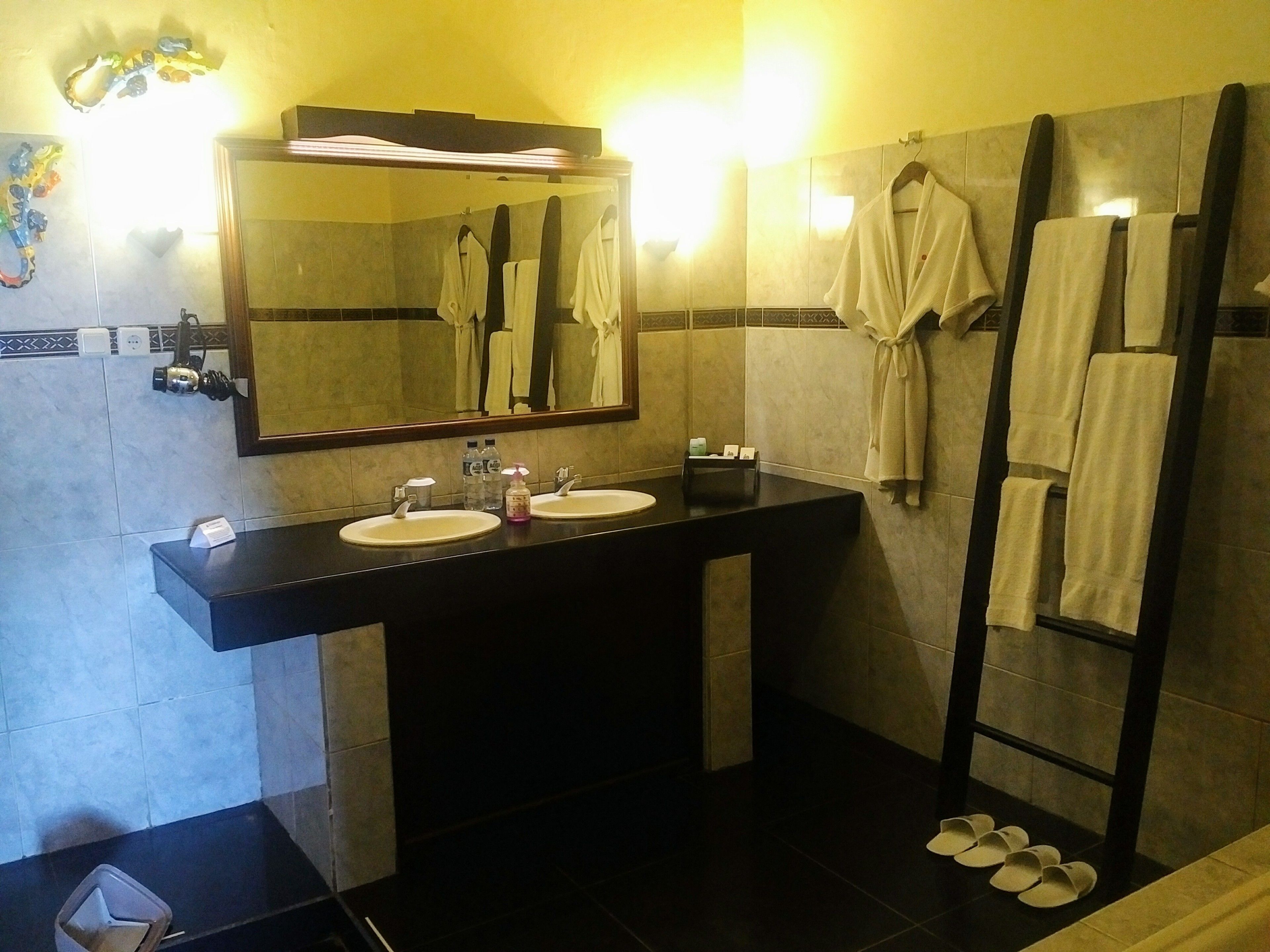 Une salle de bain avec deux lavabos, un miroir et un porte-serviettes.