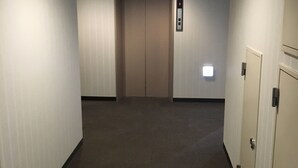 A hallway with an elevator, carpeted floor, and a door on the right. - Hotel Ohedo (Tokyo)