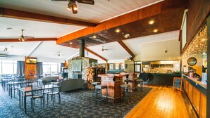 Un restaurant spacieux avec de hauts plafonds, des poutres apparentes et un bar central.